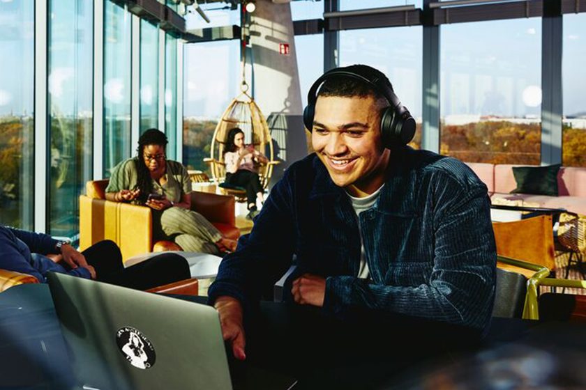 smilende mann med laptop på kafe